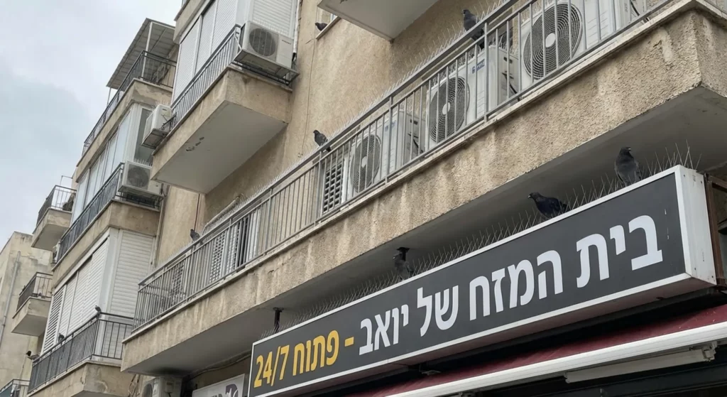 בניינים עם מרפסות, מזגנים וציפורים, כולל שילוט עם מילת המפתח "מדביר".